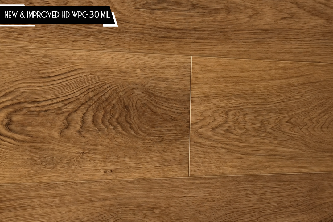 Oak wood-look flooring planks in a medium brown tone with visible grain patterns and a small black text banner in the top left corner reading 'NEW & IMPROVED HD WPC-30 MIL'.