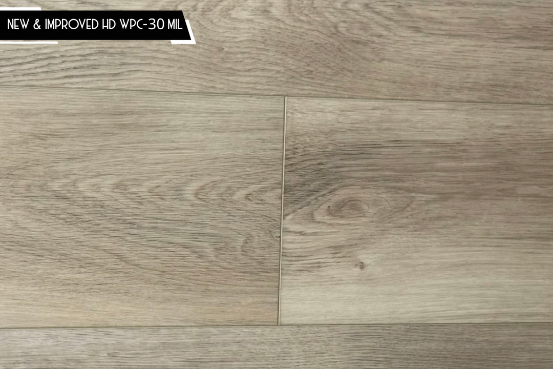Light oak wood-look flooring planks with visible grain and a black text banner in the top left corner reading 'NEW & IMPROVED HD WPC-30 MIL'.
